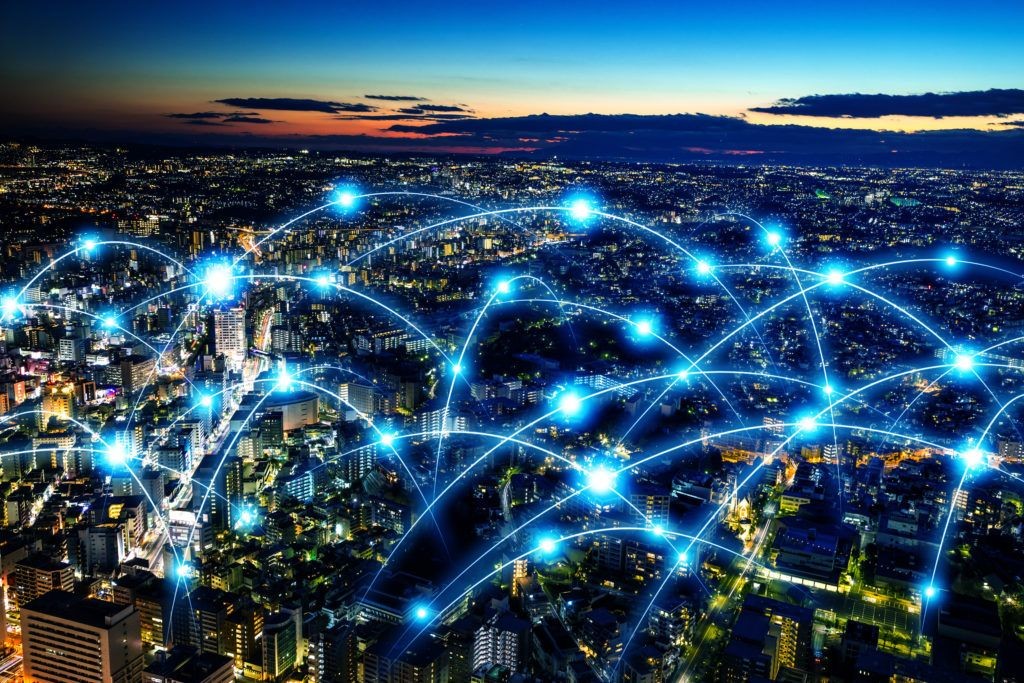 Cityscape at dusk with glowing connection points and blue lines representing a digital or communication network.