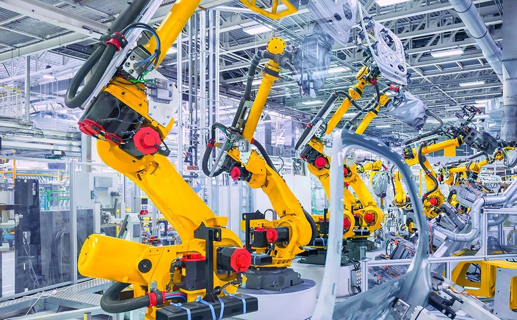 Automated yellow robotic arms assembling parts in a modern industrial manufacturing facility.